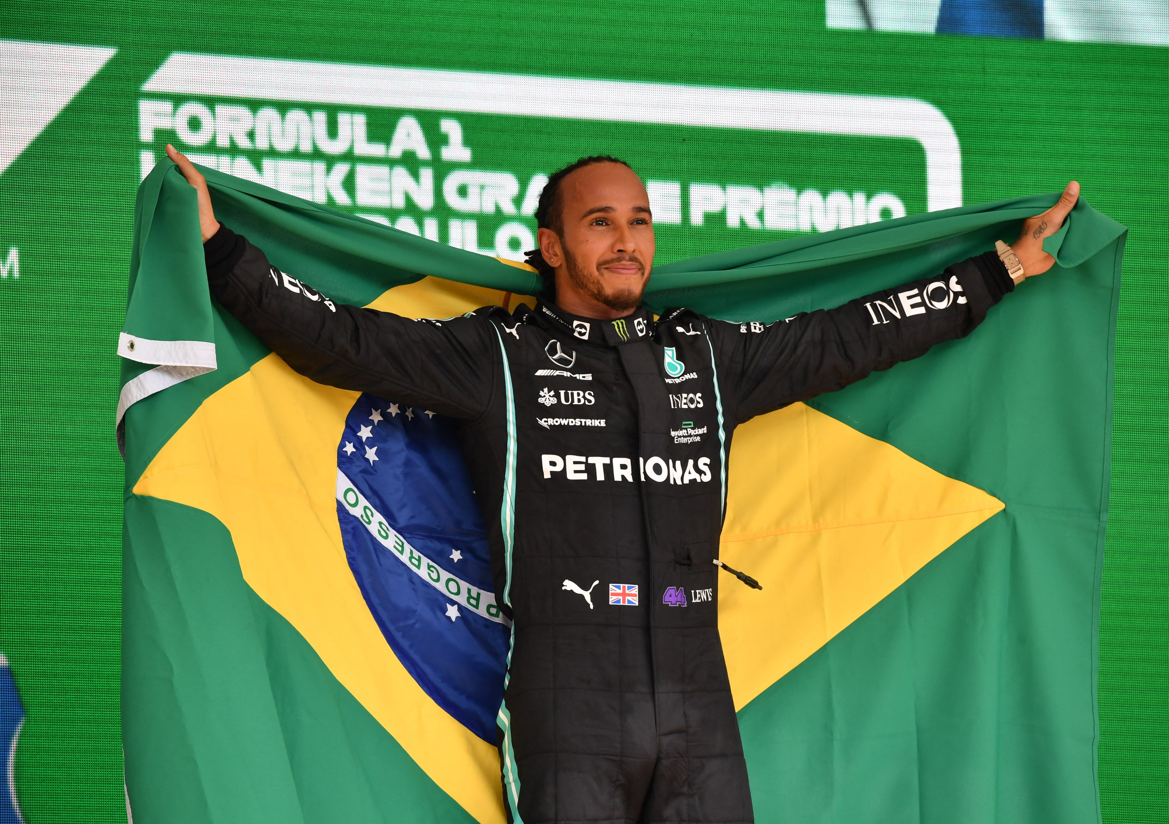 Hamilton no pódio enrolado na bandeira do Brasil